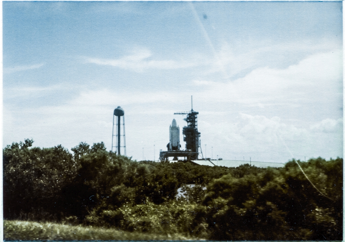 Image 021. The dawning of a new age in spaceflight manifests itself in the form of an incredible gigantic flying machine like no other that had come before it, at any time, at any place. Colombia, sitting in its launch position at the Launch Pad on top of the MLP with the RSS rolled back in its de-mate position, as seen driving along Beach Road past Space Shuttle Launch Complex 39-A, Kennedy Space Center, Florida, on the way to work at Pad 39-B which was still under construction at the time. Photograph by James MacLaren.